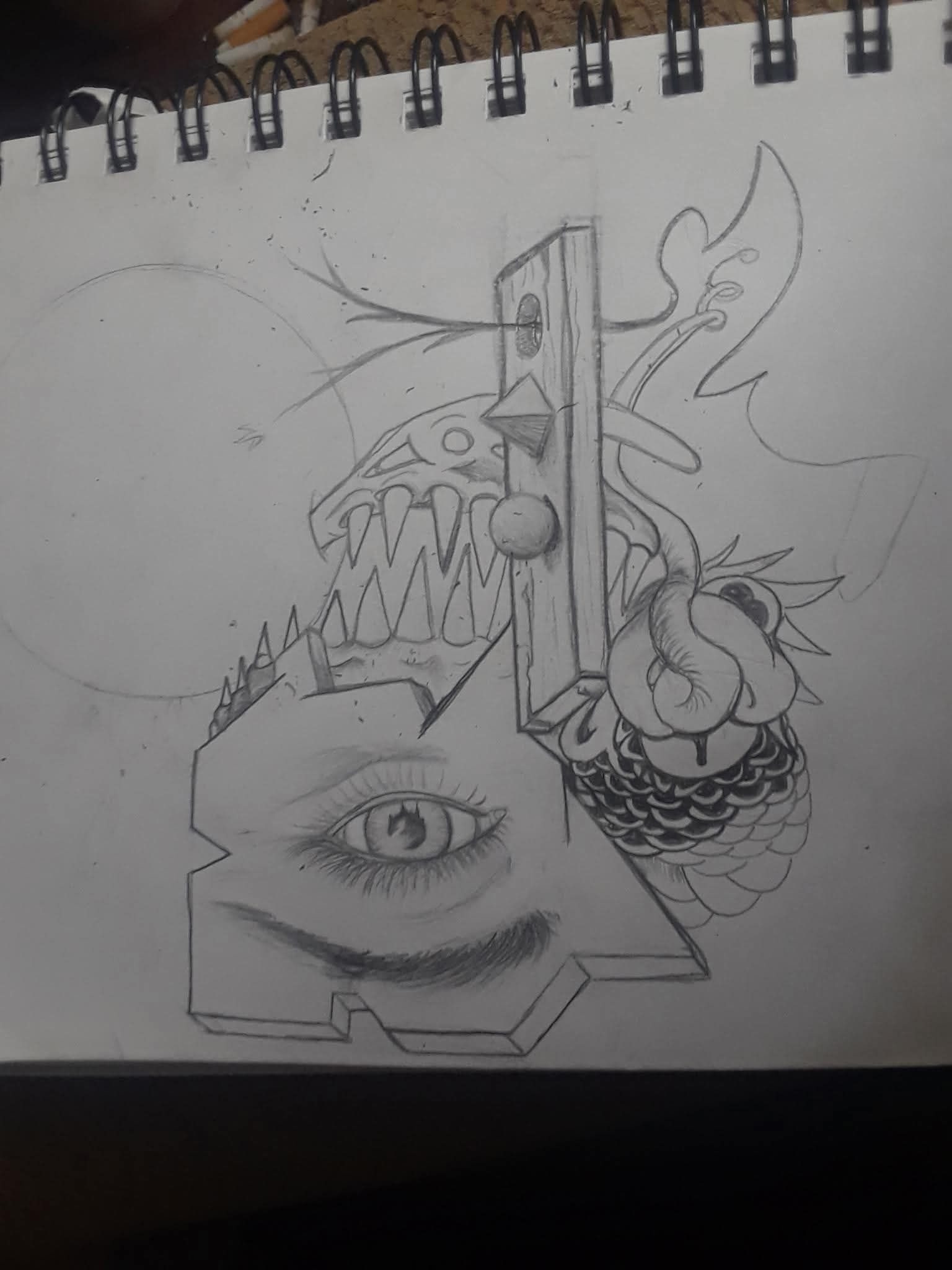 A graphite sketch on spiral-bound paper features a realistic eye, sharp teeth, geometric shapes, and a textured pattern.