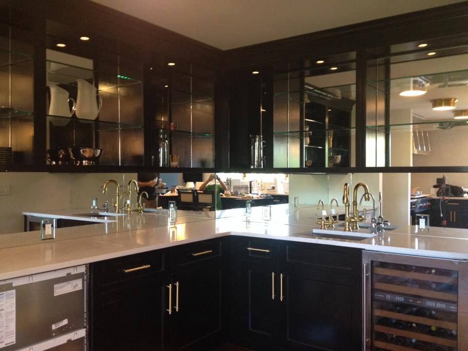 Modern kitchen with dark cabinets, marble island, sink, and wine cooler