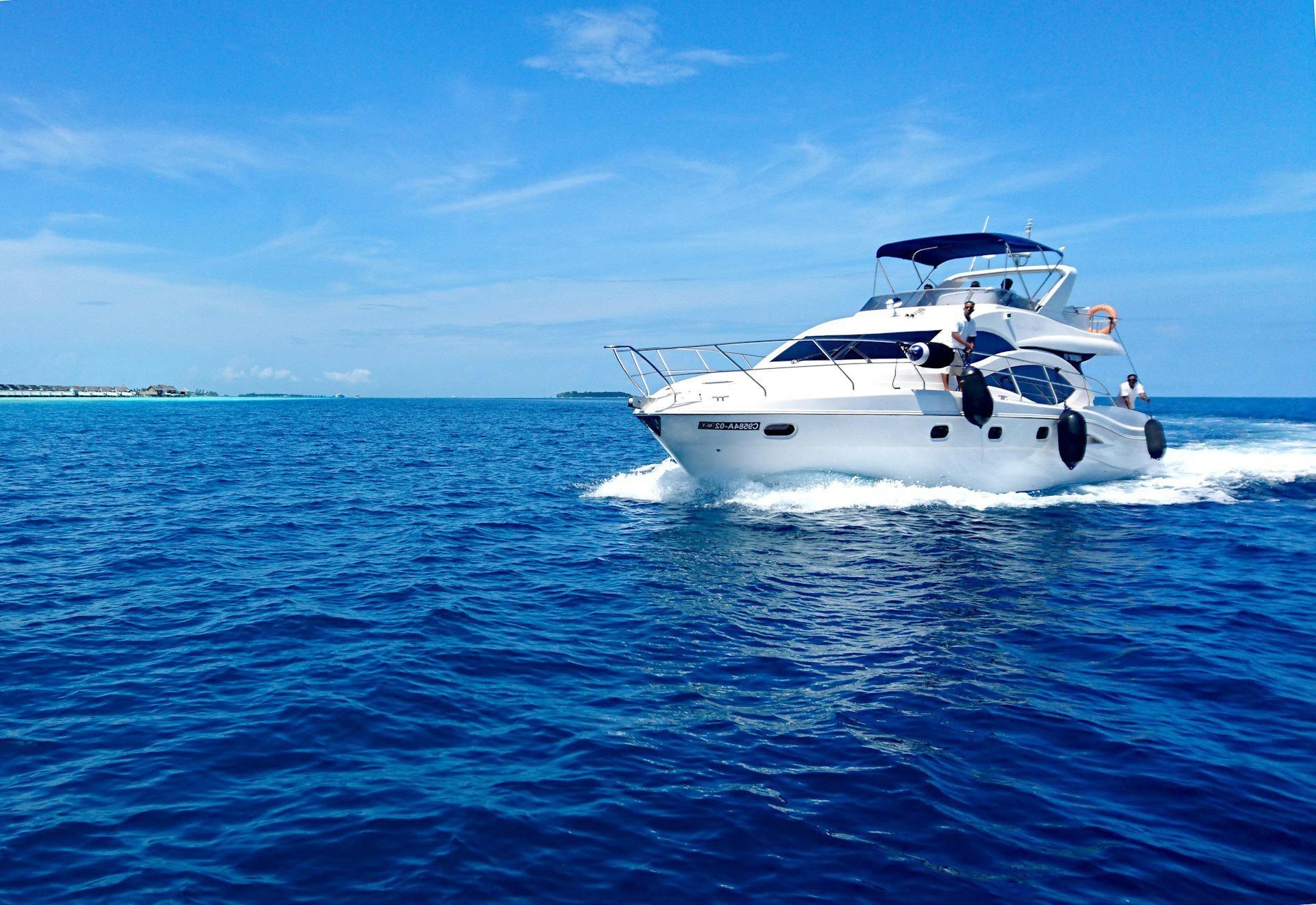White yacht sailing on deep blue water under a bright blue sky.