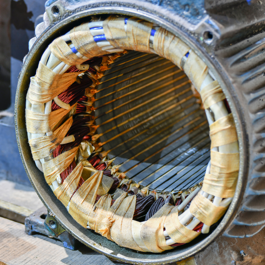 Stator windings of an electric motor. Copper wires wrapped in insulation are visible within the metallic frame.