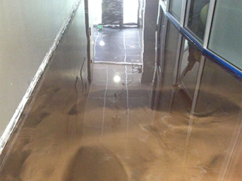 A hallway with a shiny floor and stairs leading up to a door.