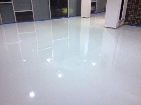 A white epoxy floor in a room with a lot of windows.