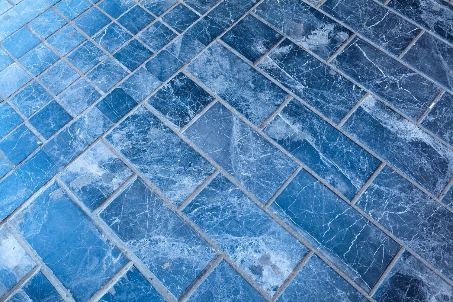 A close up of a blue tile floor with snow on it.