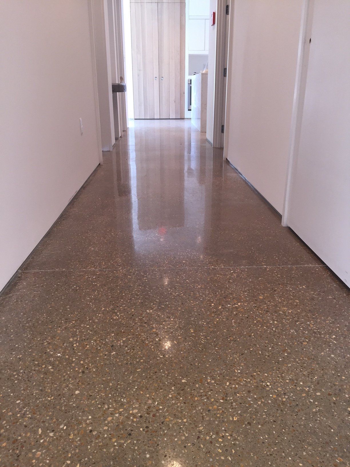 A hallway with a shiny floor and white walls