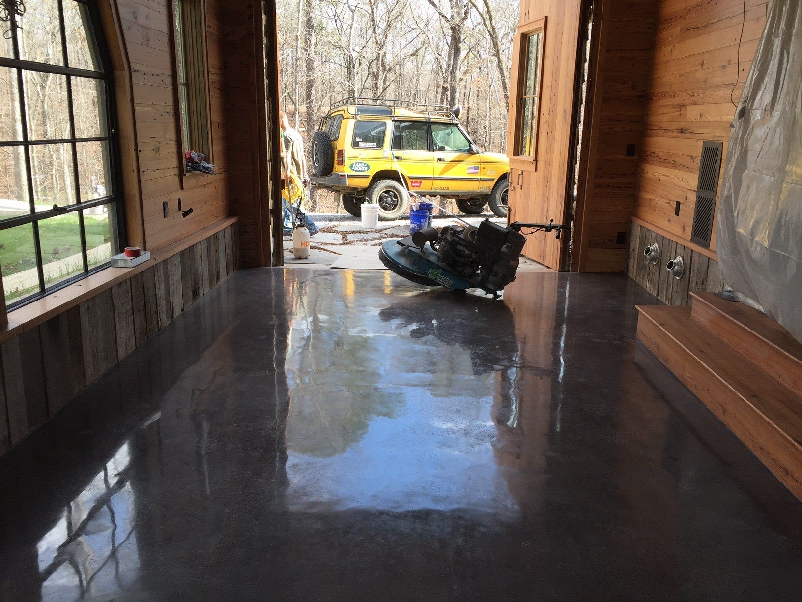 A yellow suv is parked in a garage with a grinder on the floor.