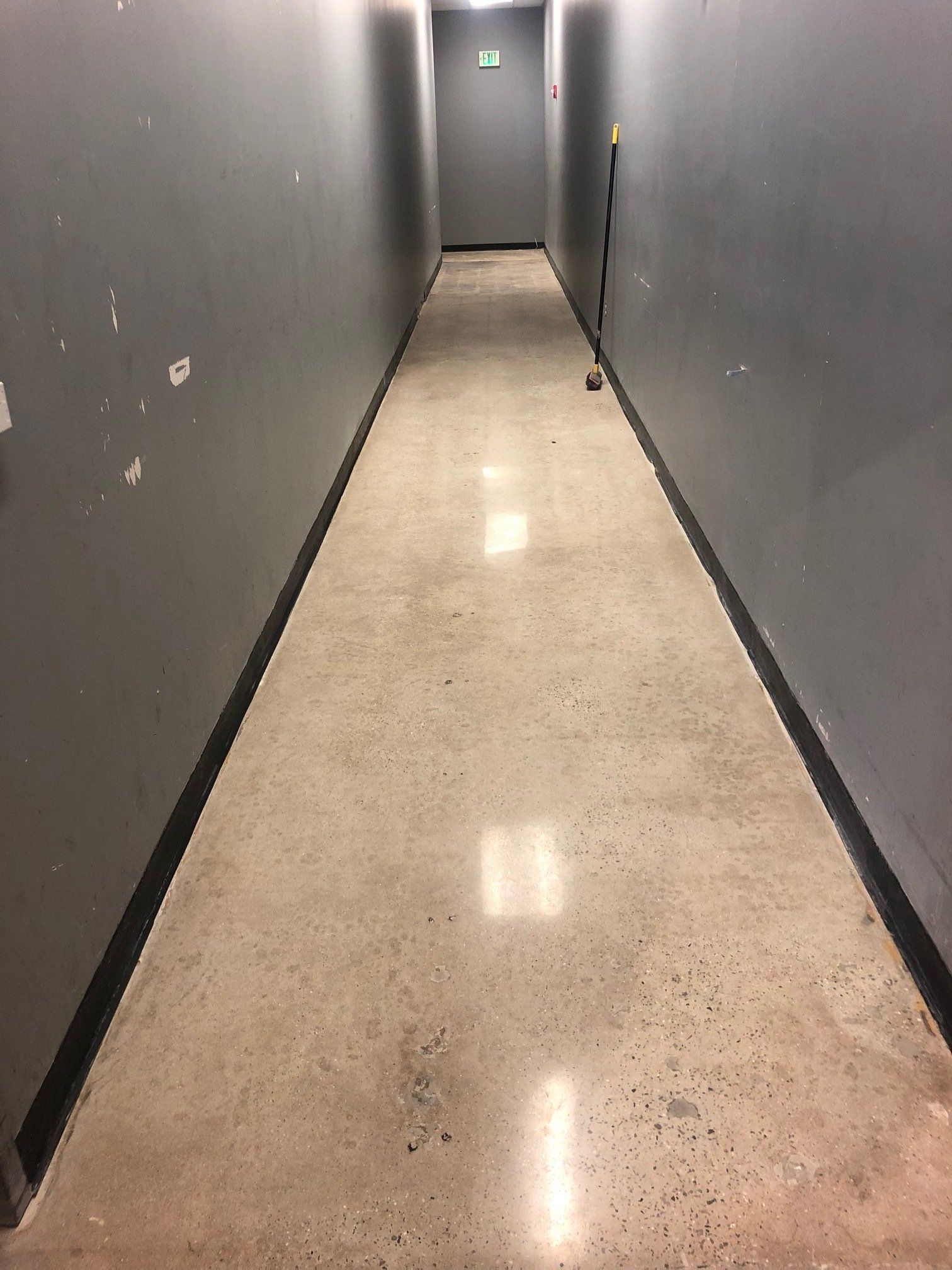 A long hallway with a concrete floor and gray walls.