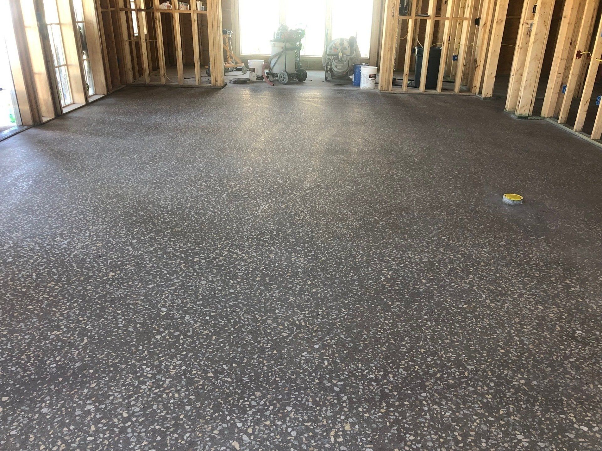 A large room with a gray carpeted floor in a house under construction.