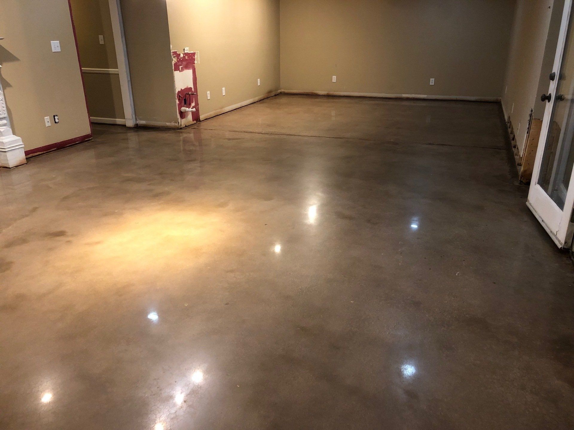 A large room with a shiny concrete floor and a door.