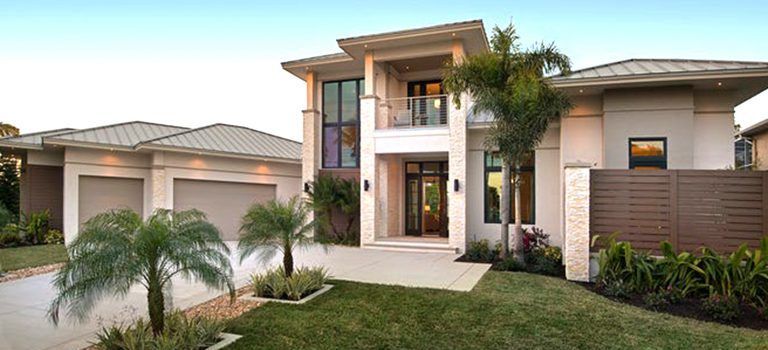 Modern two-story house with a white facade, palm trees, and a neatly landscaped front yard