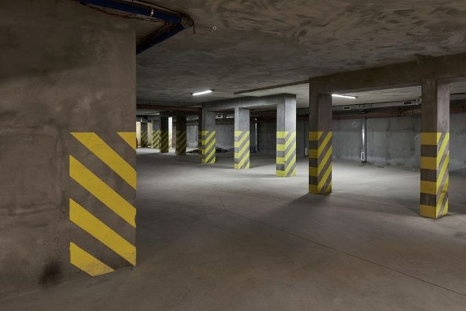 Empty underground parking garage with concrete pillars marked by yellow and black stripes