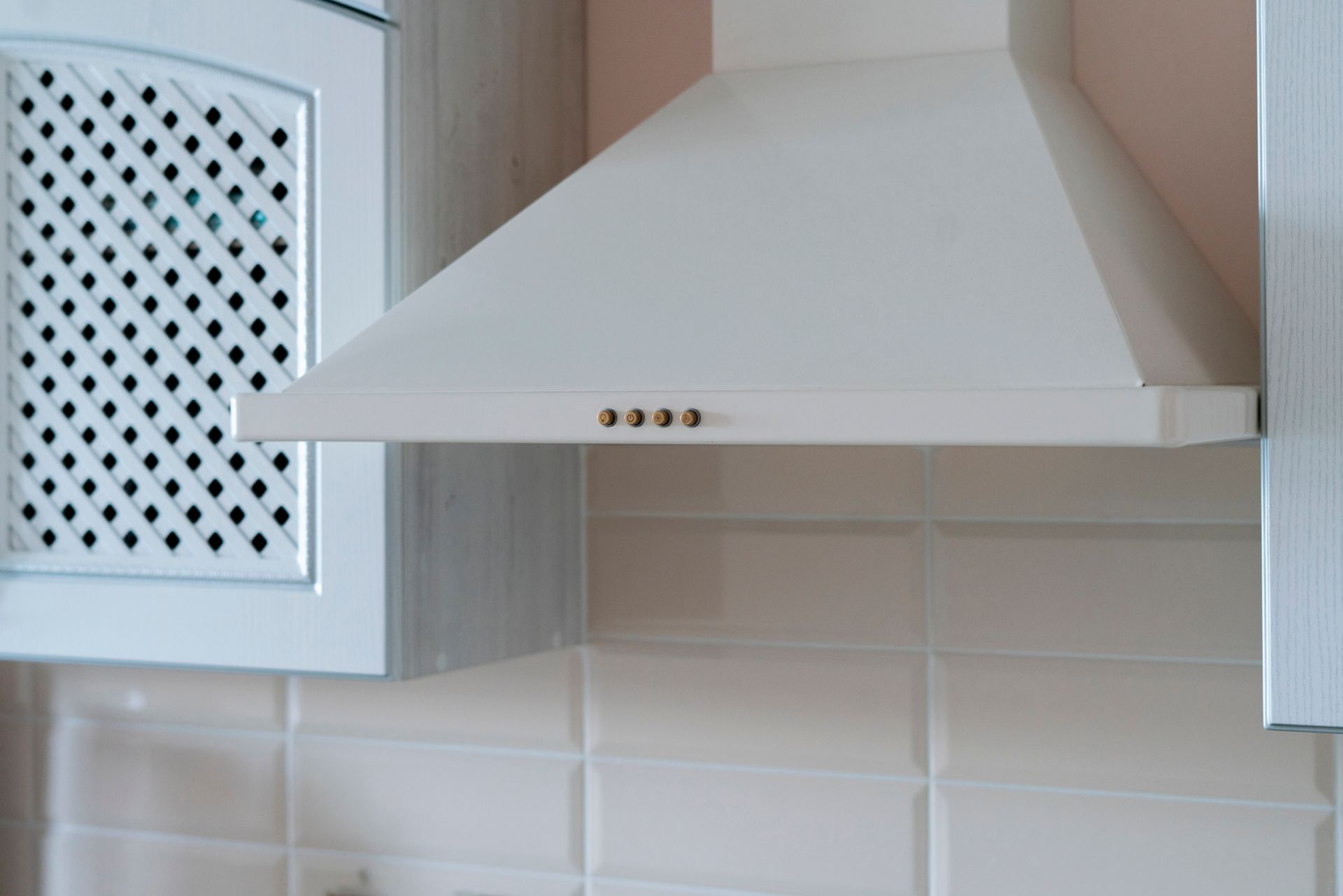 A white hood is hanging from the ceiling in a kitchen.