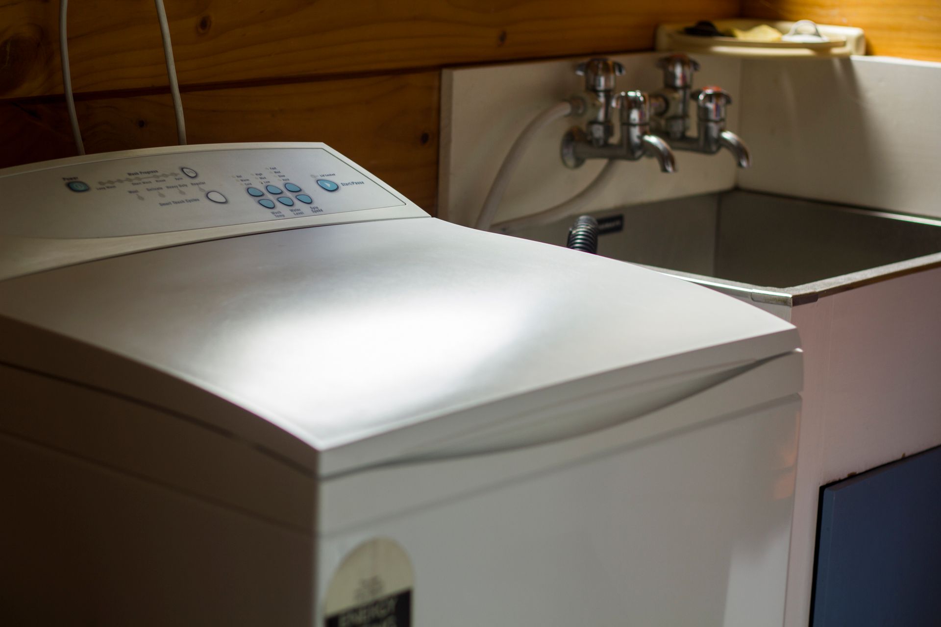 A white washing machine is sitting next to a sink.
