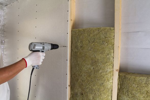 Soundproofing Insulation — Worker With Electric Screwdriver Fastening Drywall To Wooden Timber With Insulation in Houston, TX