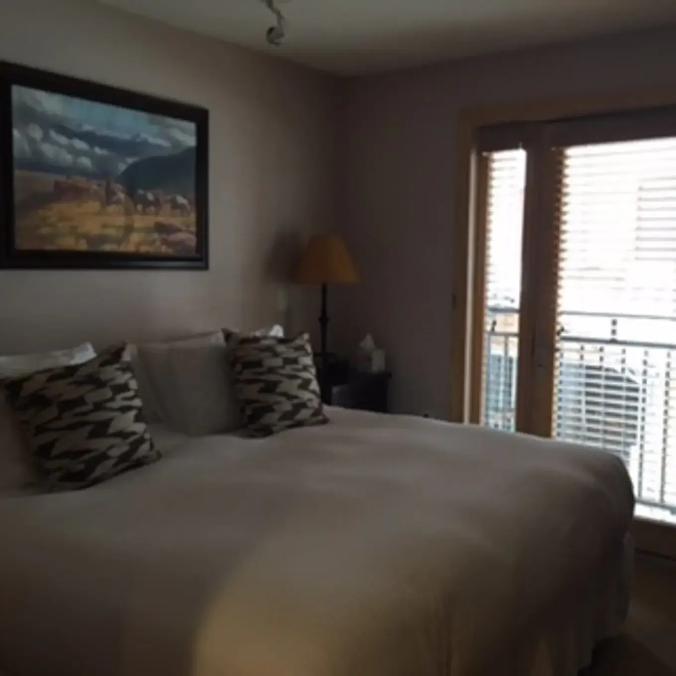 A bedroom with a painting on the wall above the bed