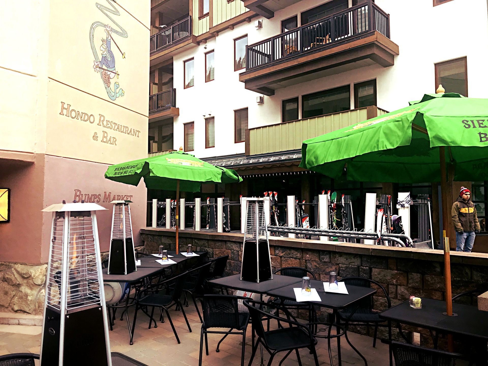 A restaurant with green umbrellas and tables outside