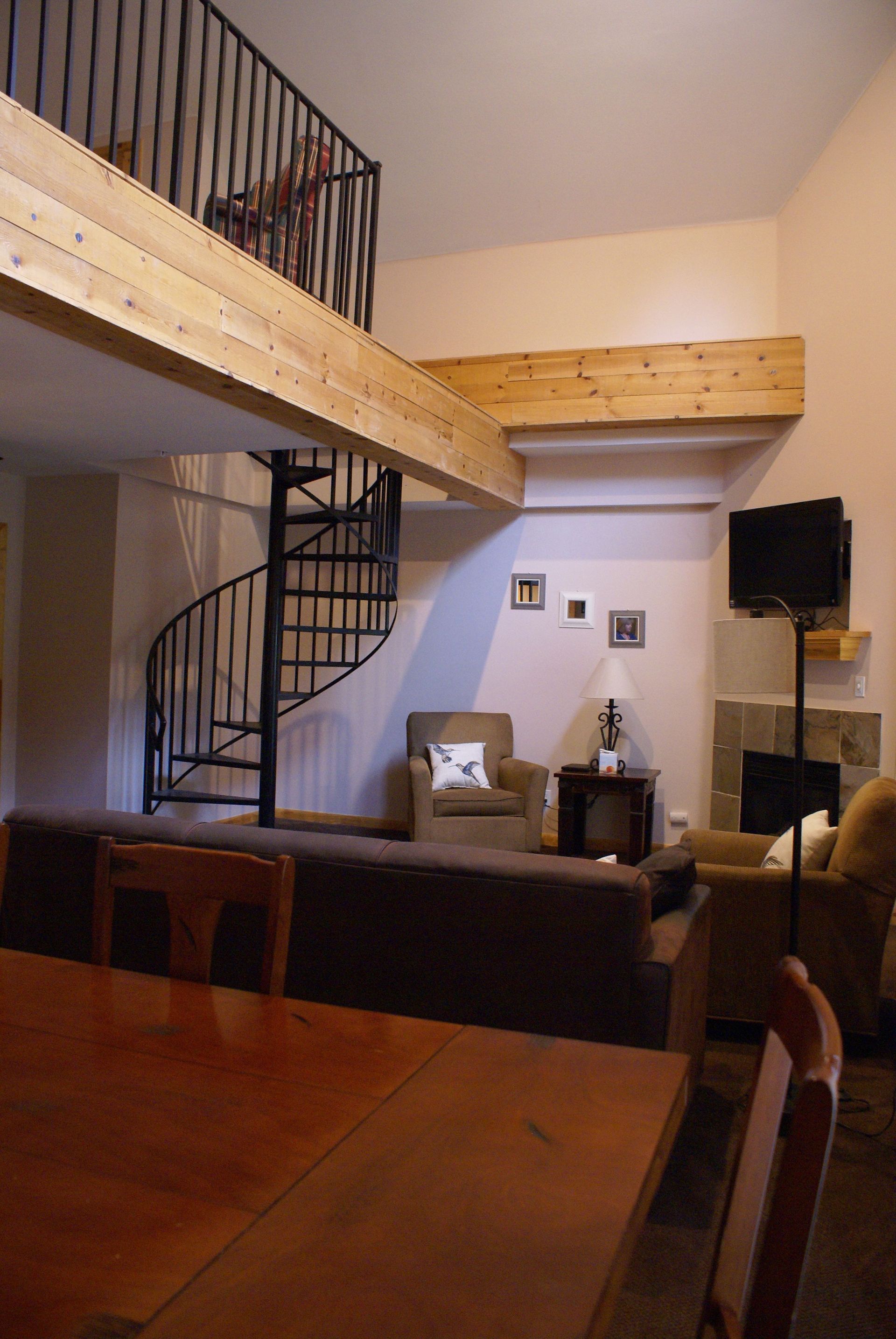A living room with a spiral staircase leading to the second floor