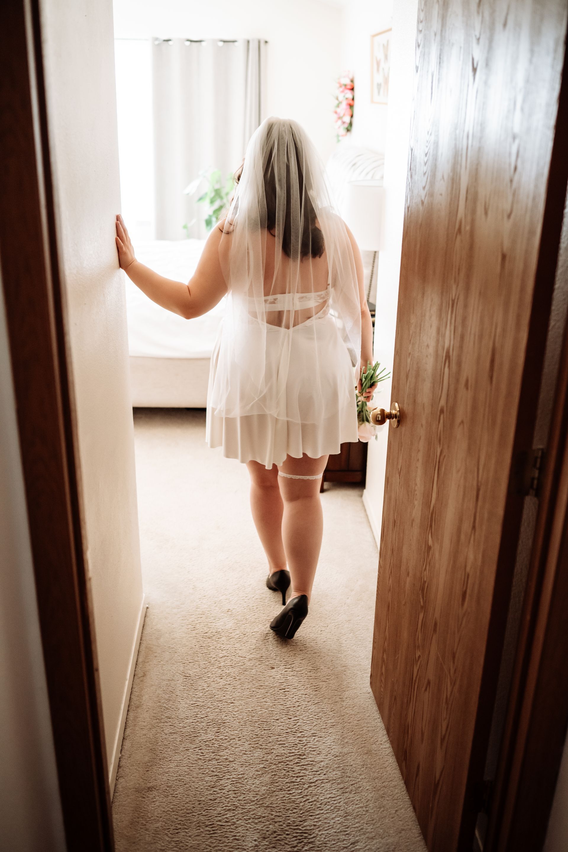 A woman in a white dress and veil is walking down a hallway.