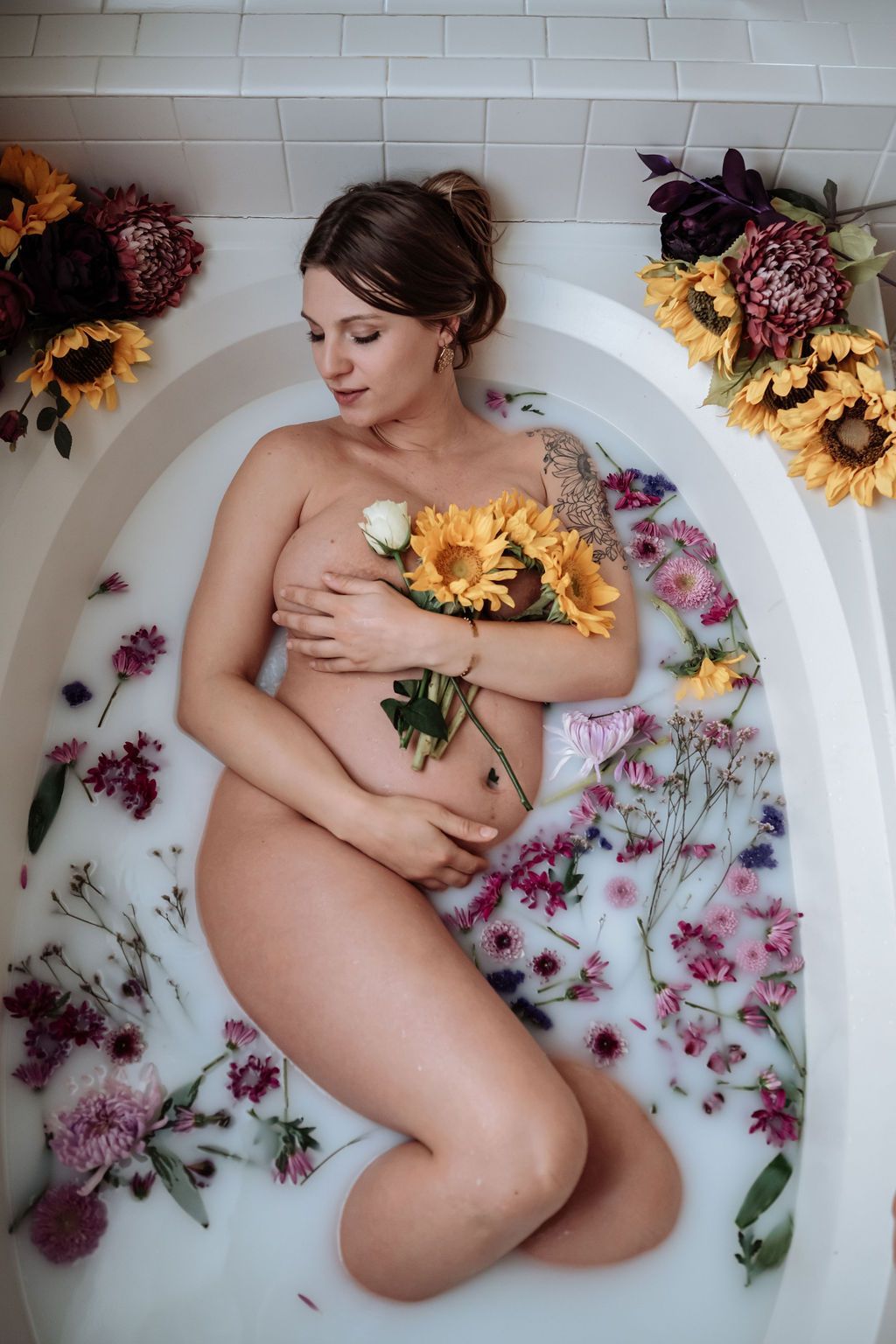 Pregnant mother laying in a bathtub with milky water and flowers