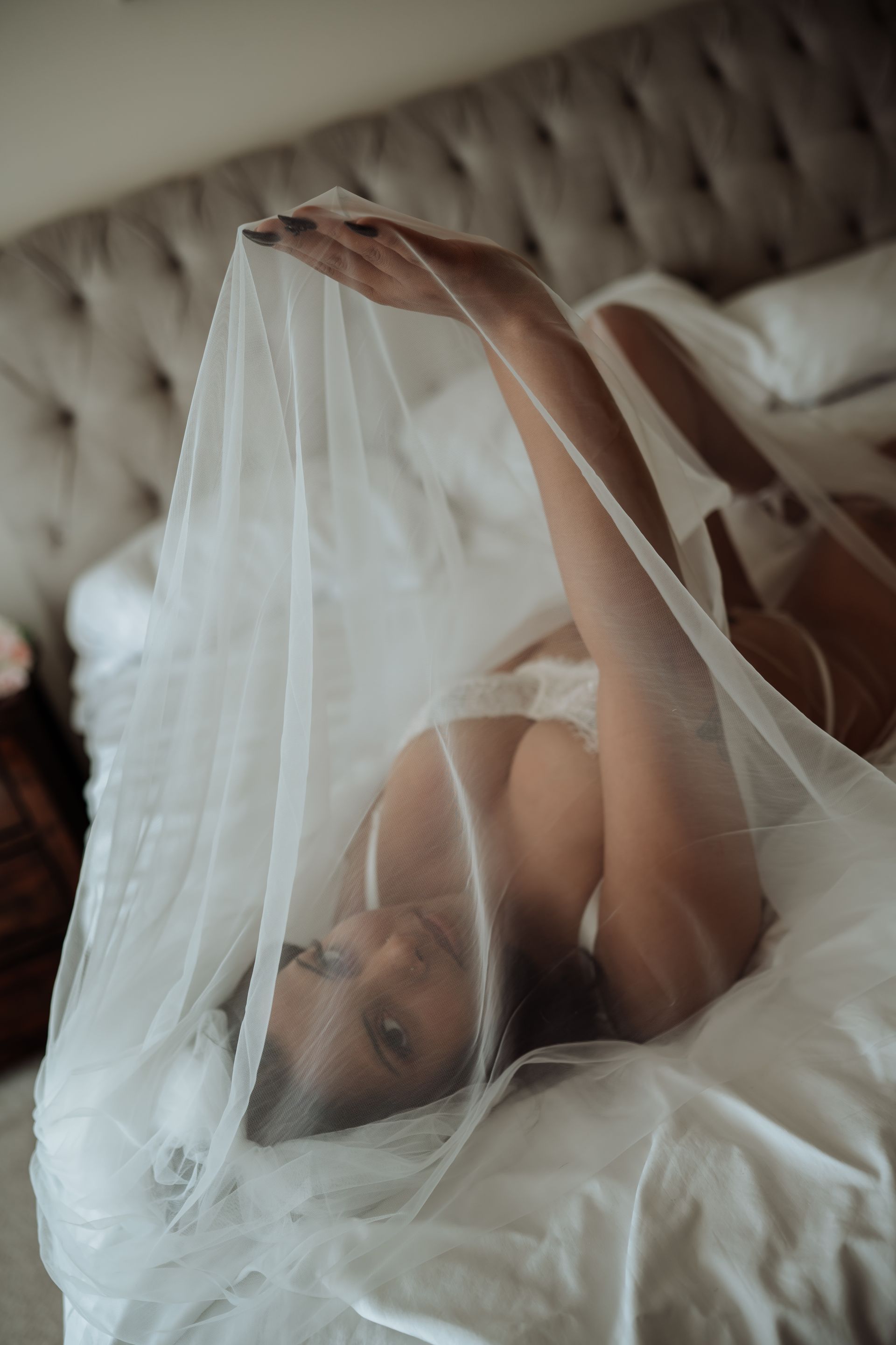 A woman is laying on a bed covered in a veil.