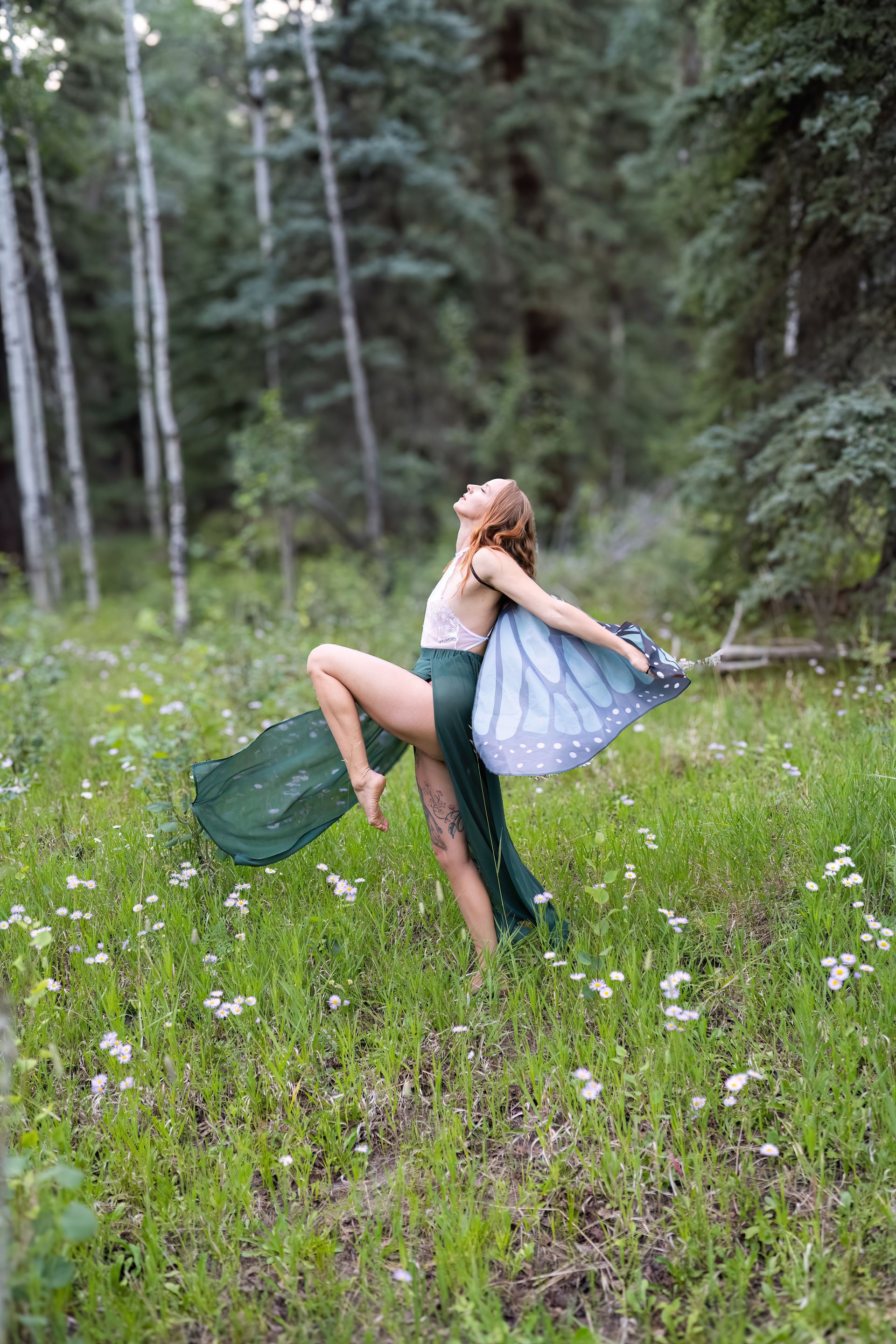 A woman is dancing in a field of flowers in the woods.