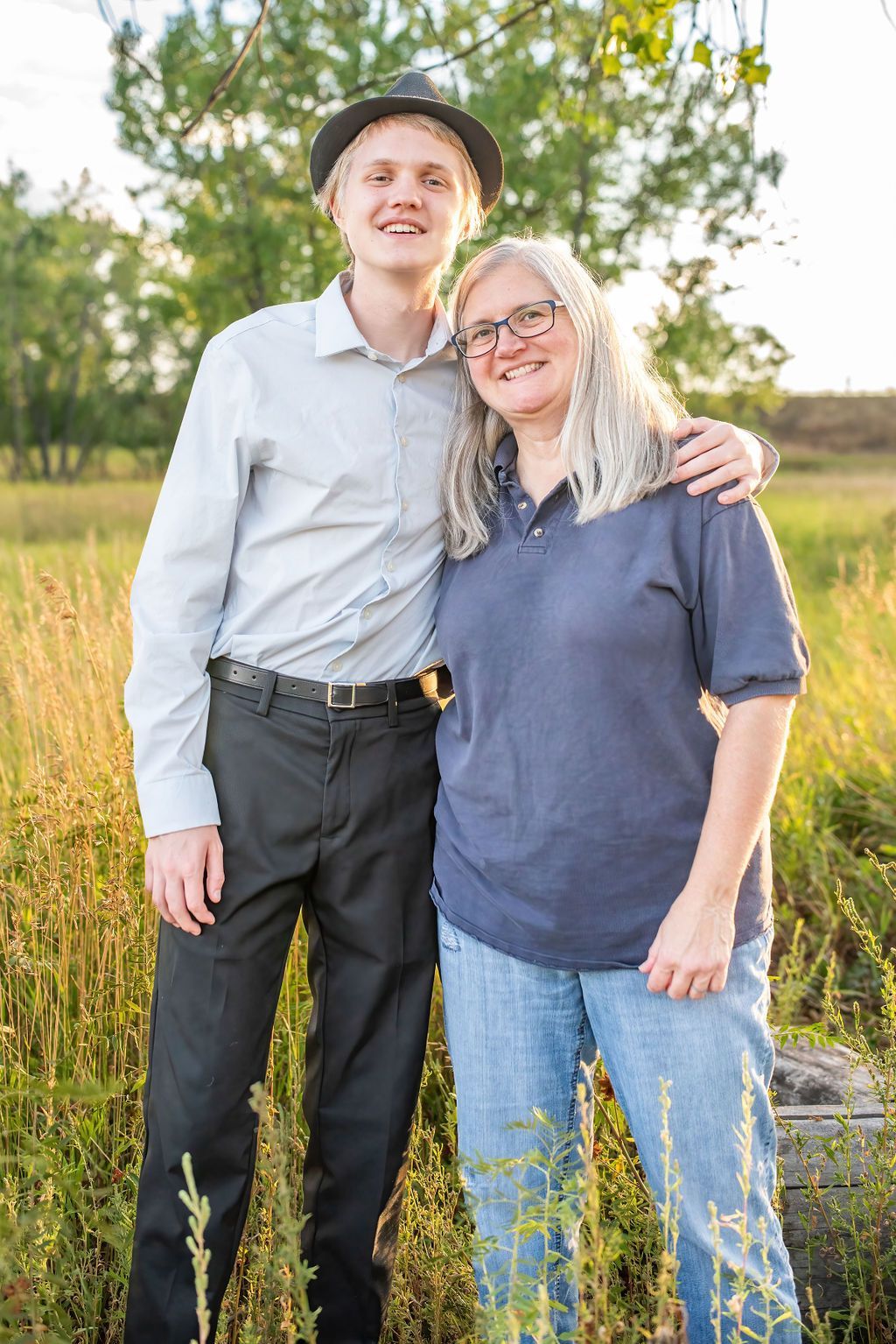 A man and a woman are posing for a picture in a field.