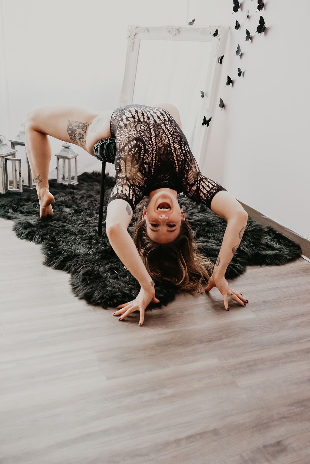 A woman is doing a handstand on the floor in front of a mirror.