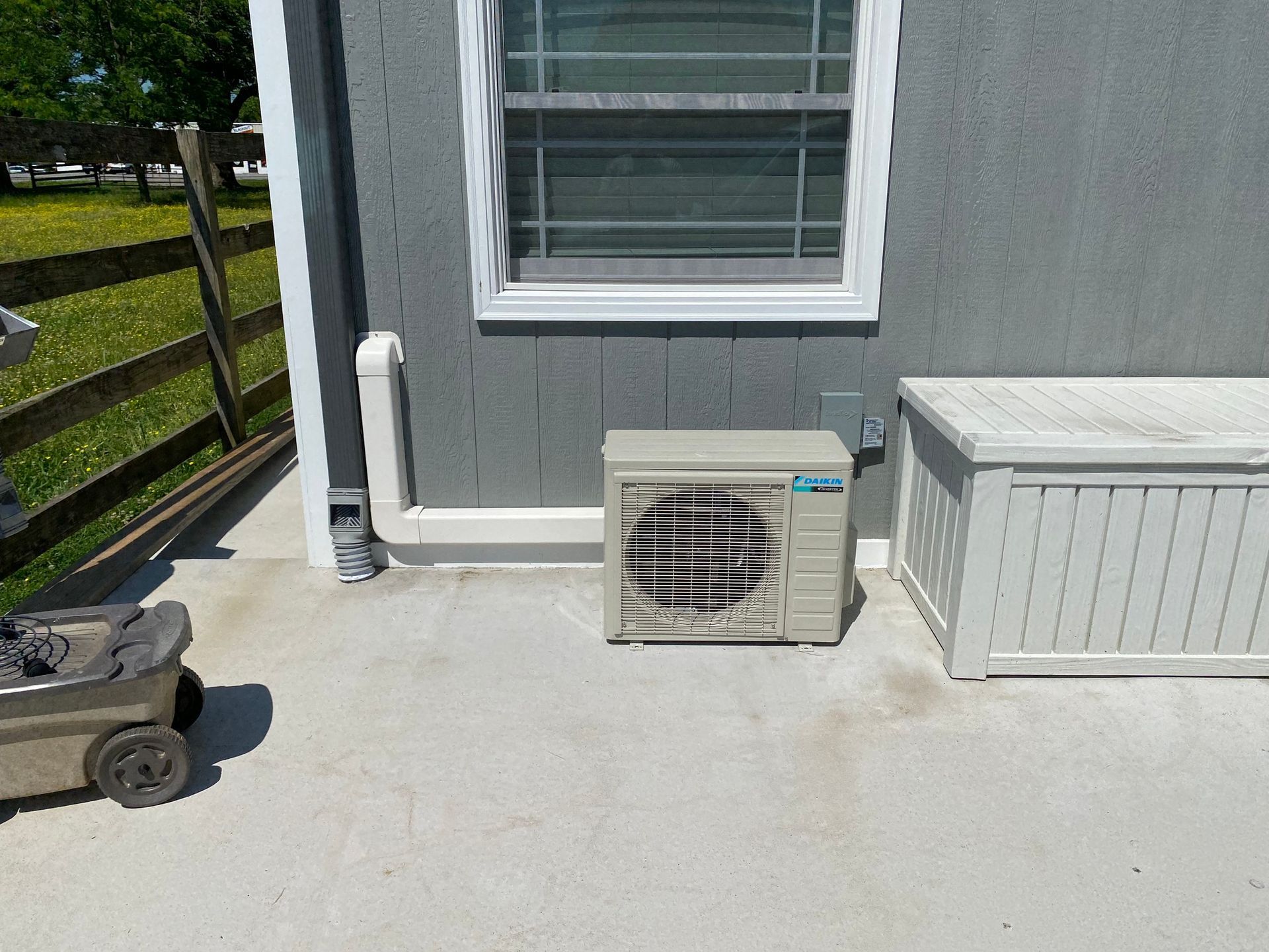 An air conditioner is sitting outside of a house next to a window