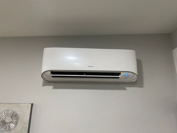 A white air conditioner is hanging on a wall in a room.