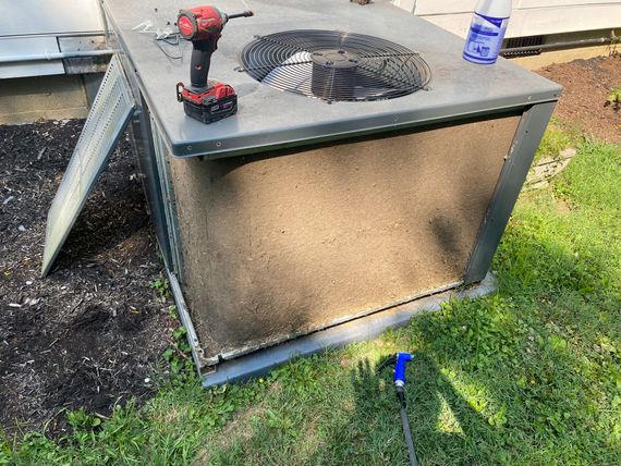 A drill is sitting on top of an air conditioner.