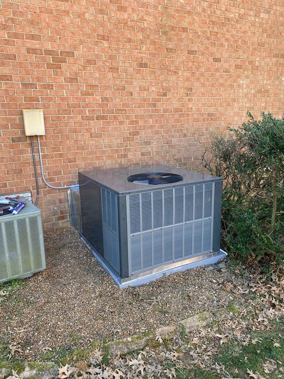 Two air conditioners are sitting outside of a brick building.