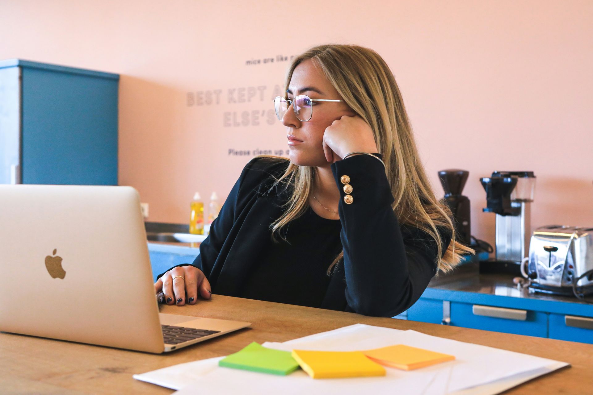 Uma mulher está sentada à mesa usando um laptop.