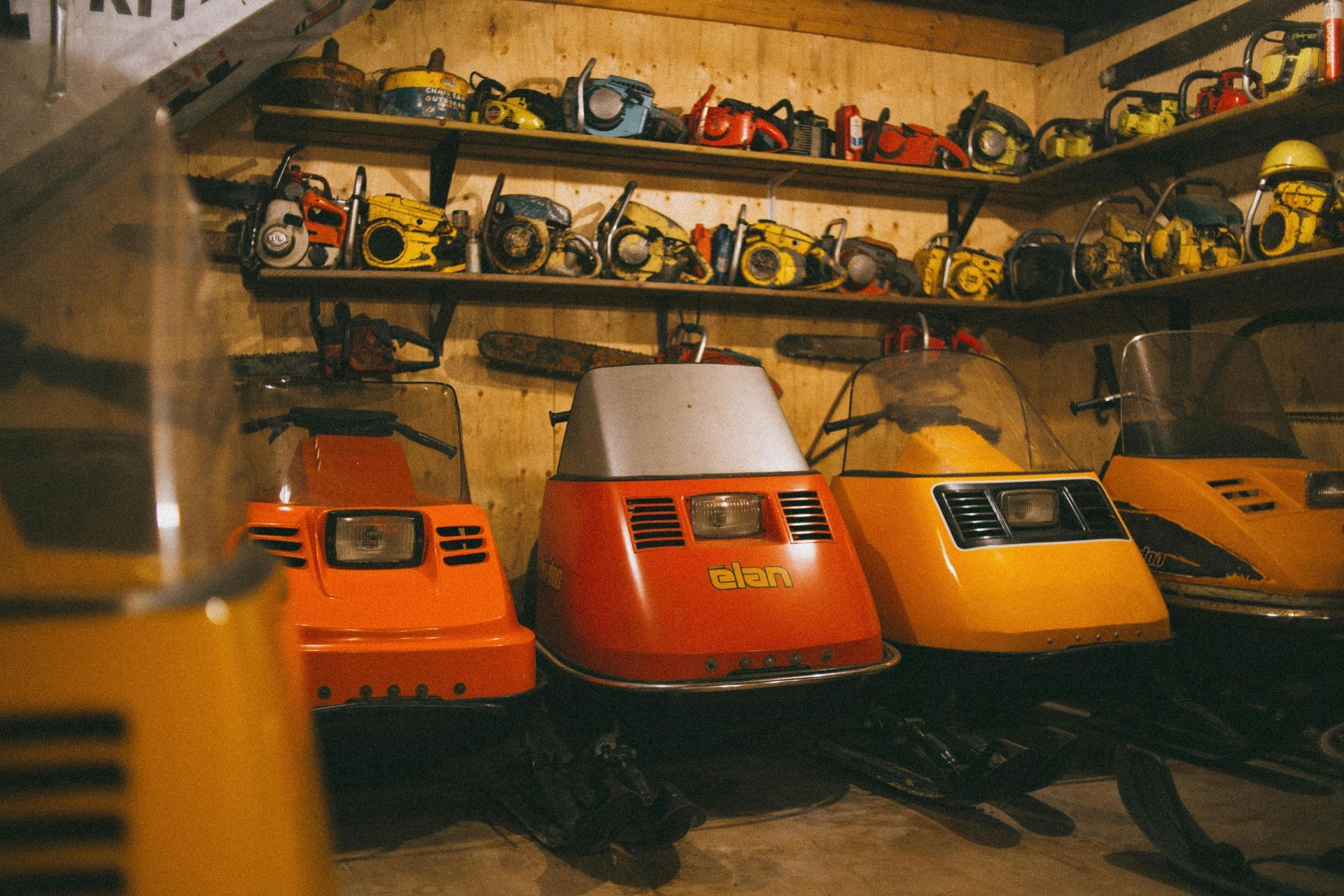 A bunch of snowmobiles are parked in a garage