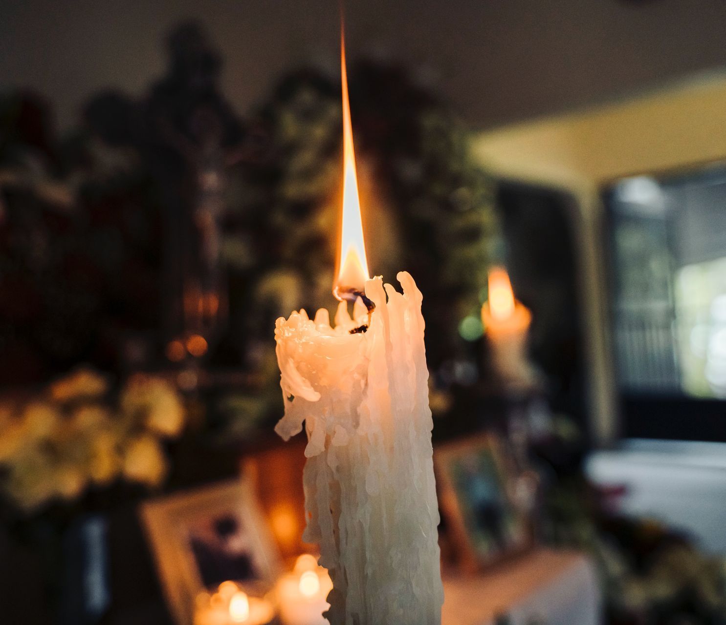 A close up of a lit candle in a dark room
