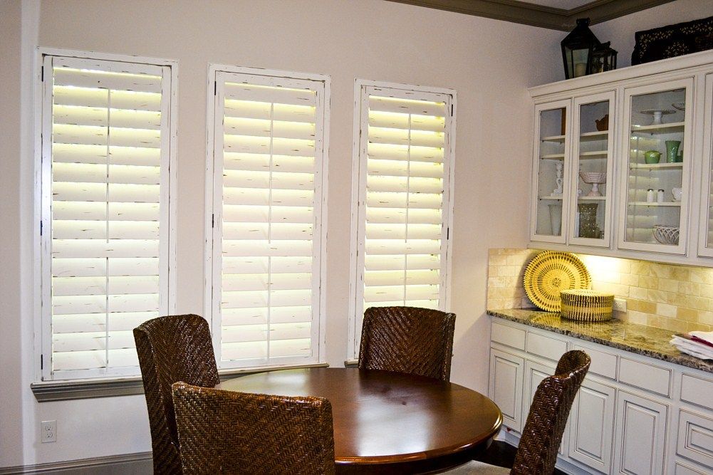 A kitchen with a table and chairs and shutters on the windows