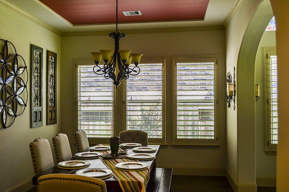 A dining room with a long table and chairs and a chandelier hanging from the ceiling.
