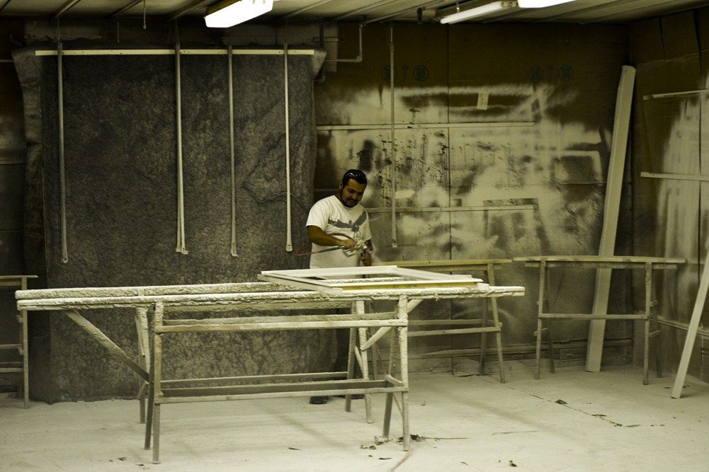 A man in a white shirt is working on a piece of wood