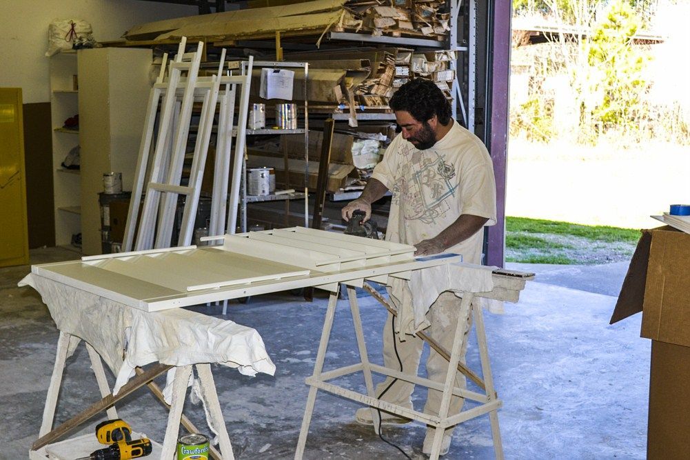 A man is sanding a piece of wood in a workshop.