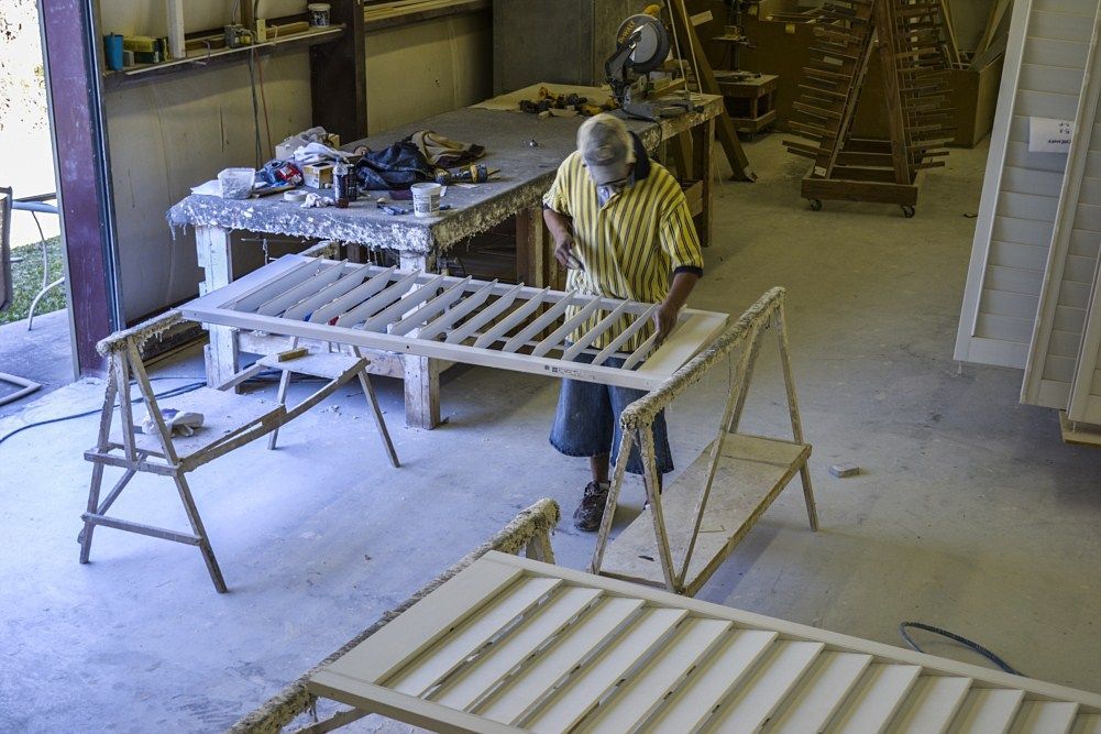 A man is painting a piece of wood in a workshop.
