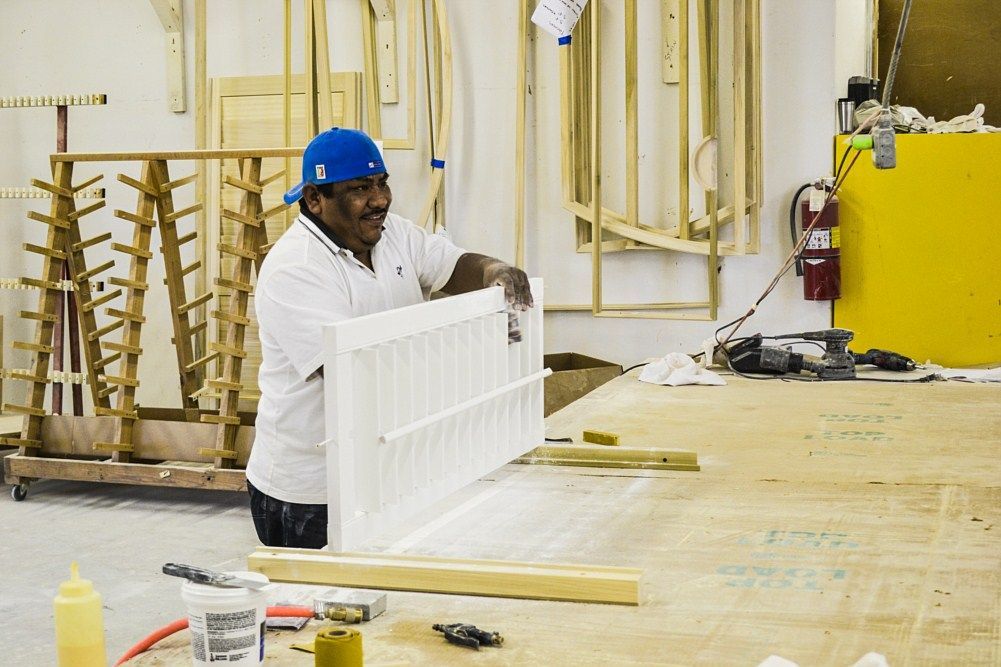 A man is holding a piece of wood in a workshop.