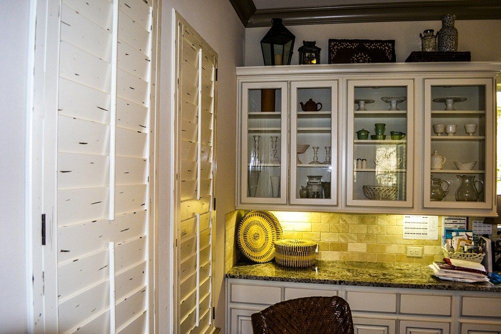 A kitchen with white cabinets and glass doors