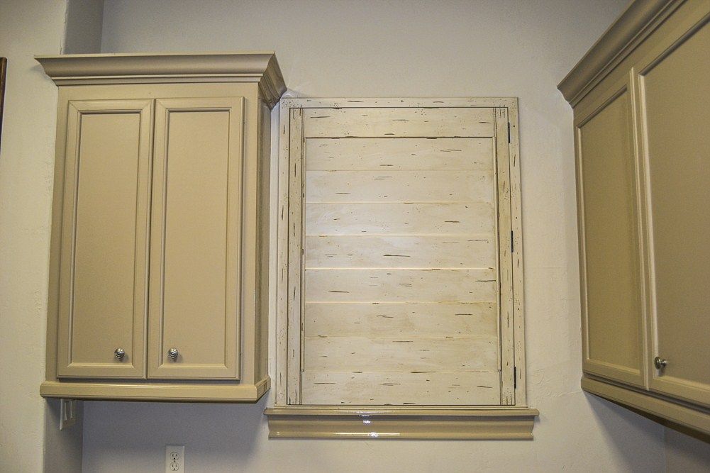 A laundry room with two cabinets and a window