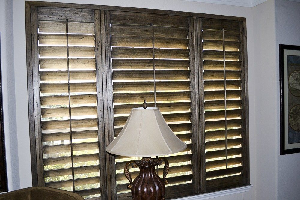 A lamp is sitting in front of a window with shutters