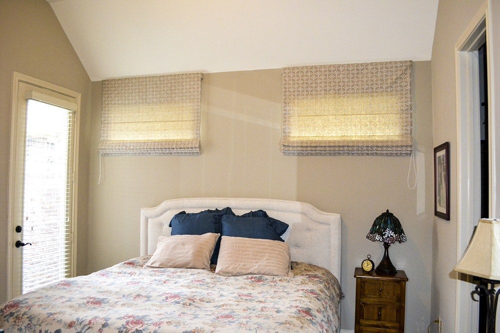 A bedroom with a bed , nightstand , lamp and sliding glass door.