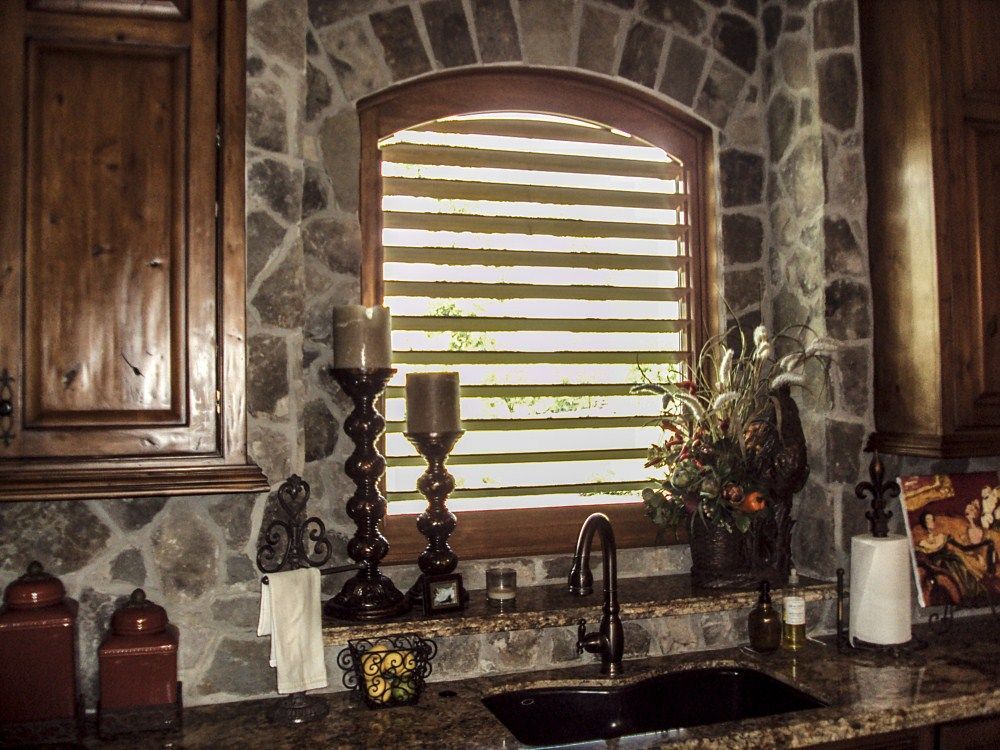 A kitchen with a sink and a window with blinds