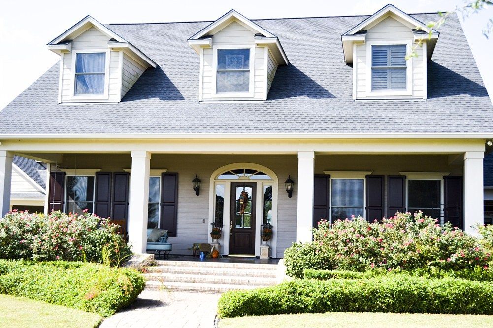 A large white house with a gray roof and black shutters