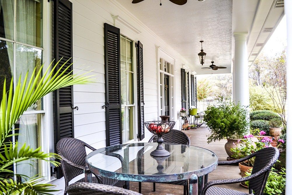 There is a table and chairs on the porch of a house.