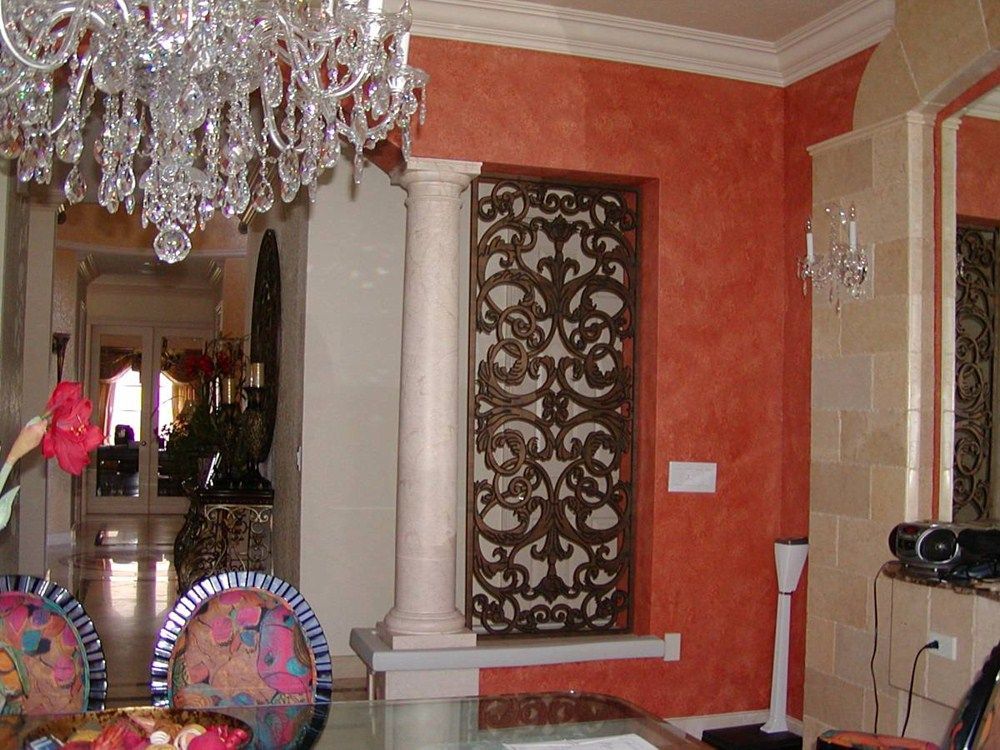 A wooden door with a wrought iron design is on a stone wall.