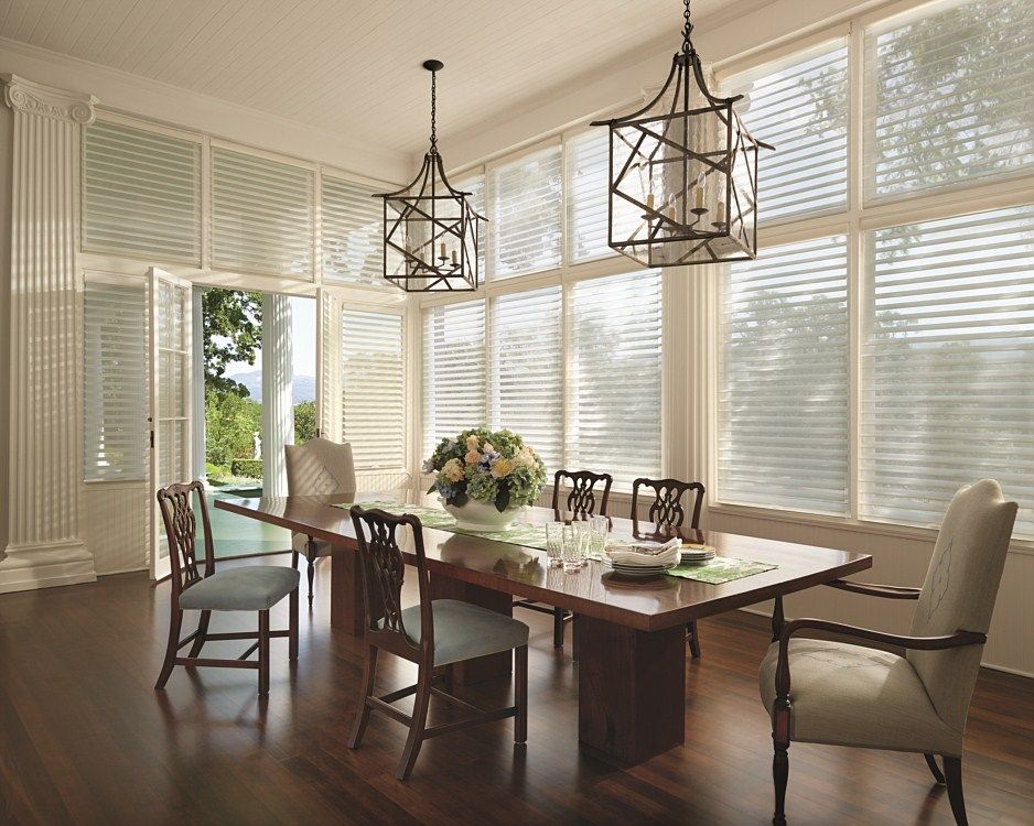 A dining room with a long table and chairs and lots of windows.