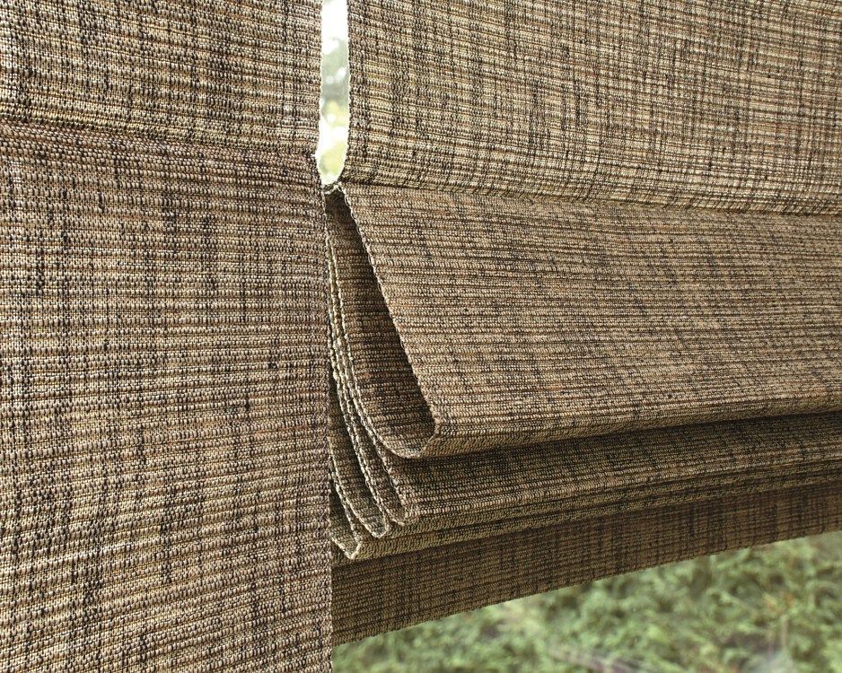 A close up of a brown roman shade hanging on a window.