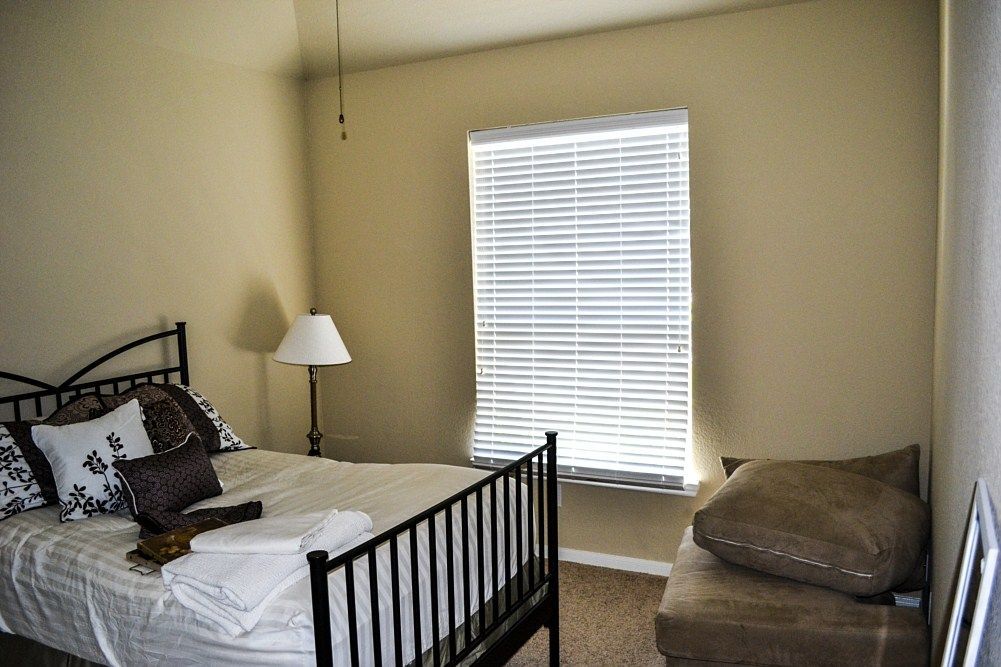 A bedroom with a bed , couch , lamp and window.